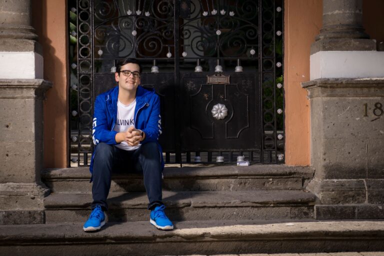 Young man wearing a blue jacket sits on stone steps in Guadalajara, Mexico.