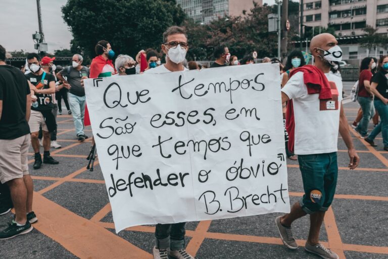 Activists in Rio de Janeiro protest with a powerful message on a banner.
