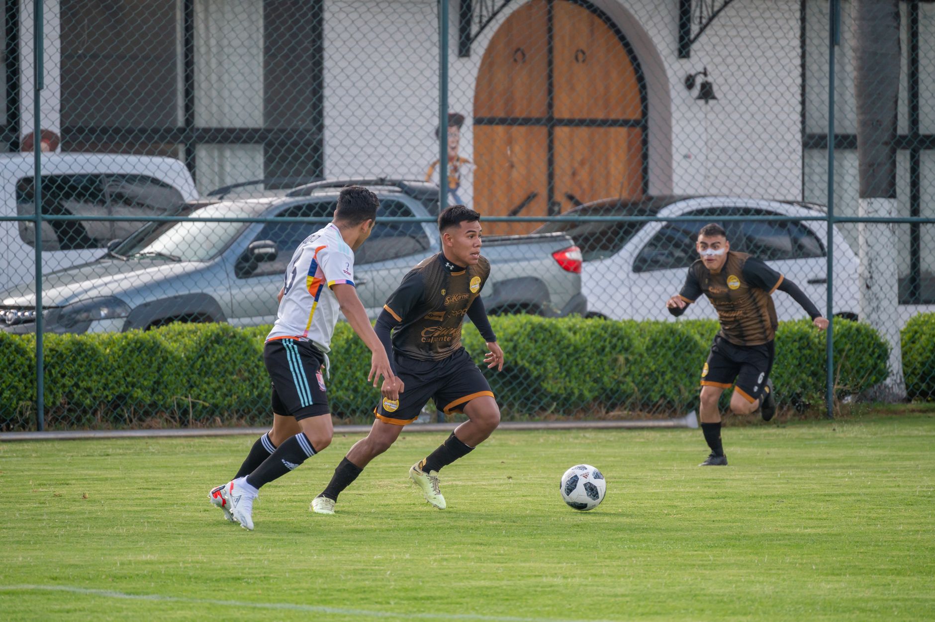 Action-packed scene of players competing in a football match on a sunny day in Texcoco, Mexico.
