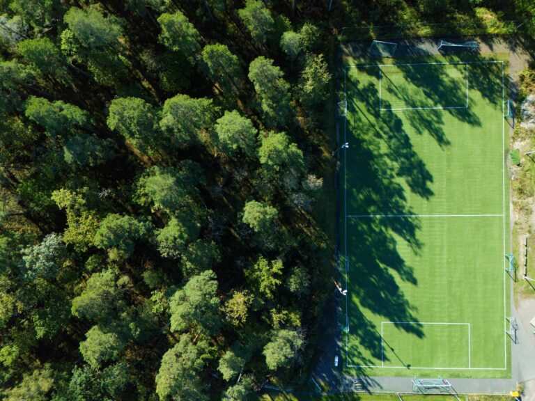 Aerial view of a lush forest beside a soccer field in Jönköping, Sweden.