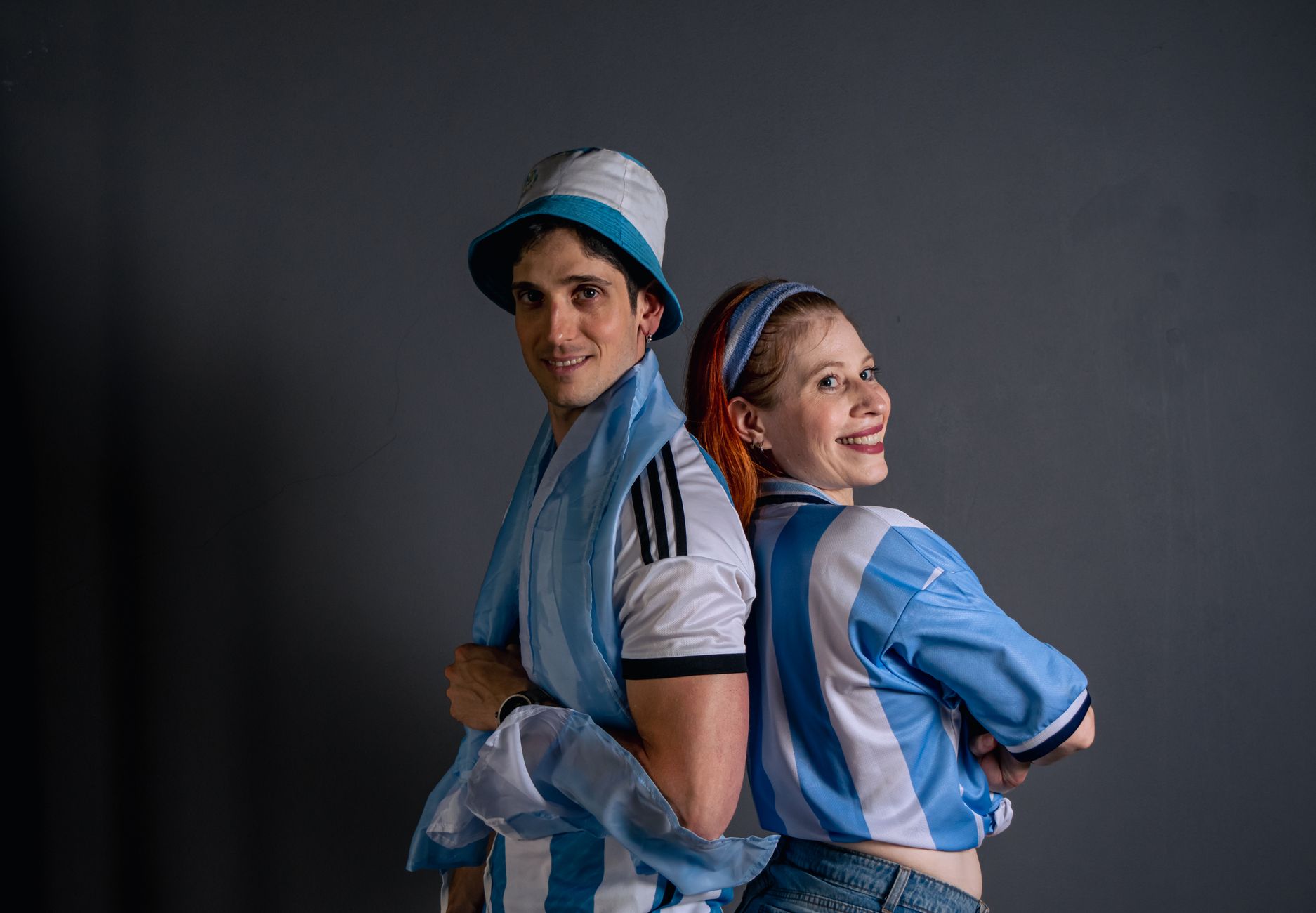 Happy soccer fans in blue and white jerseys celebrating sports indoors.