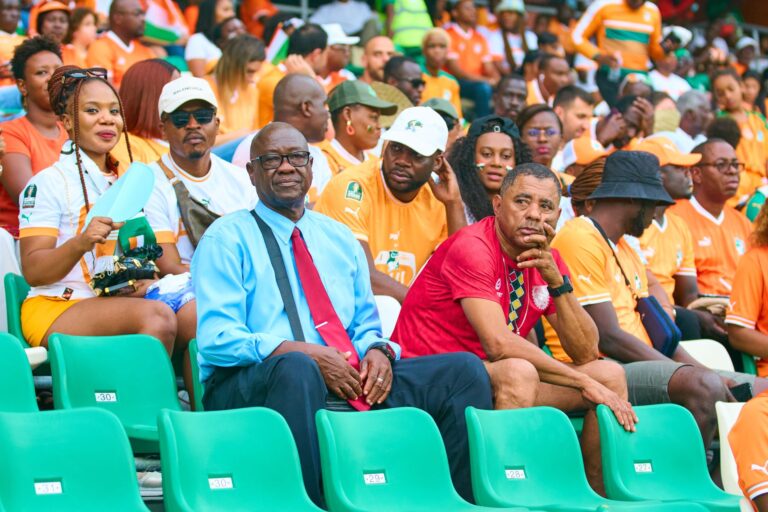 Cheerful crowd of diverse football fans enjoying a live match in a vibrant stadium.