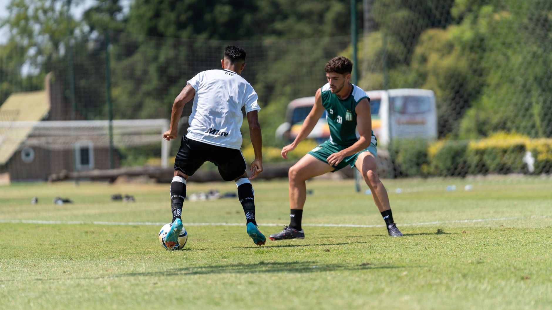 Two soccer players engage in a training match on a sunny outdoor field.