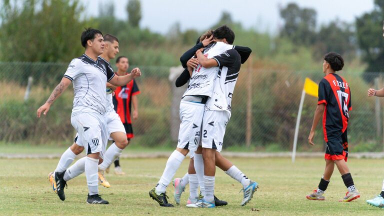 Young soccer players celebrate a goal during a match on a grassy field.
