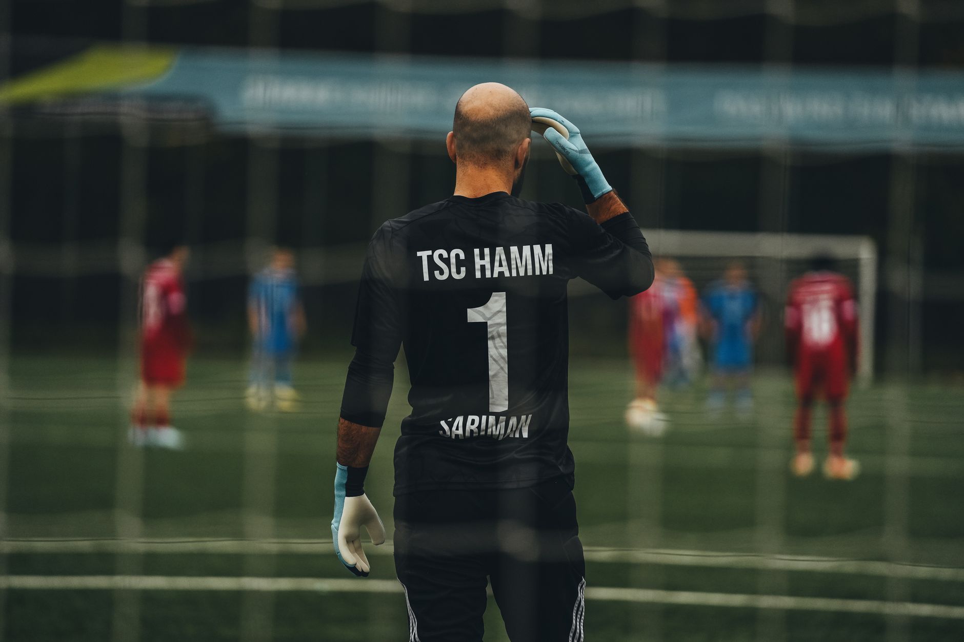 A soccer goalkeeper stands ready for a penalty kick on a field.