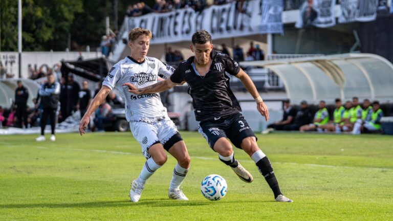 Two soccer players competing fiercely during a match on a sunny day.