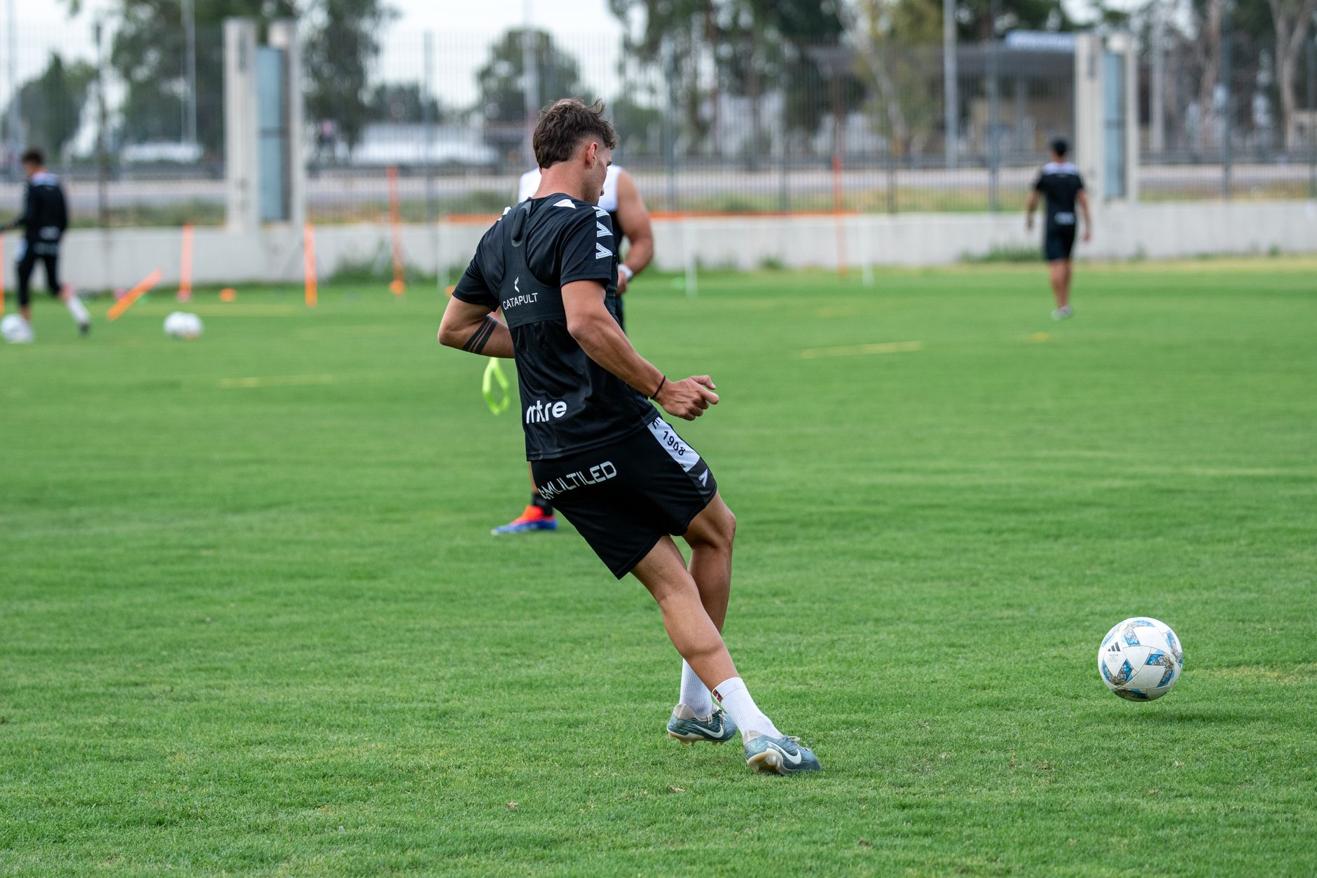 A male soccer player practices on an outdoor field during the day.