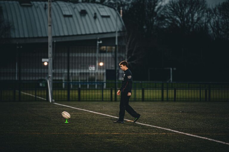 Rugby player sets up for a kick on an empty field in England.