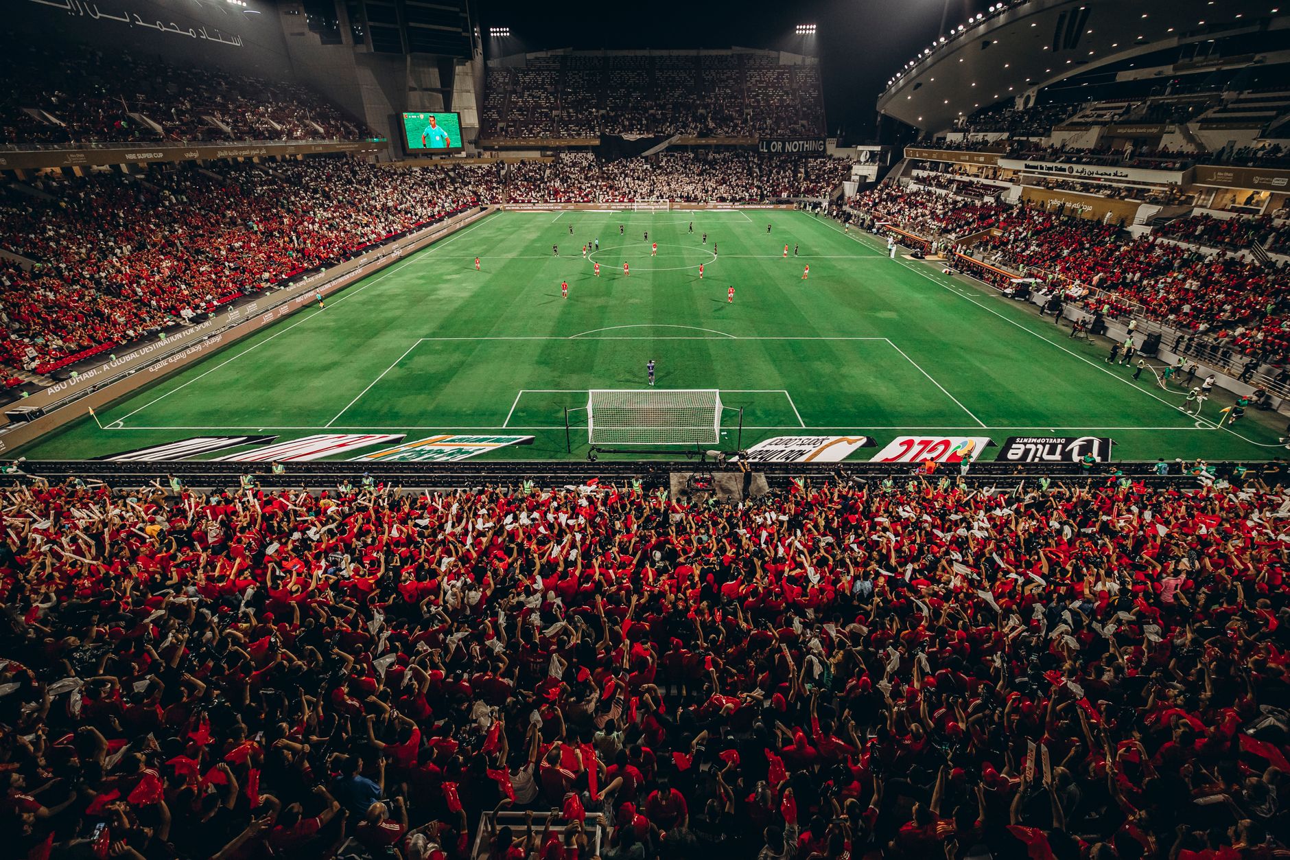 A thrilling nighttime football match with a vibrant crowd in Abu Dhabi stadium.