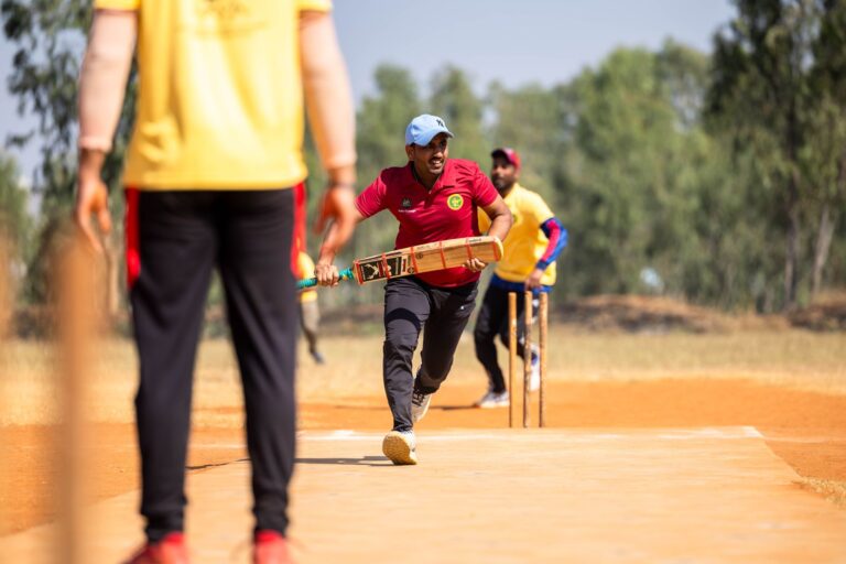 Dynamic scene of a cricket player running between wickets outdoors.
