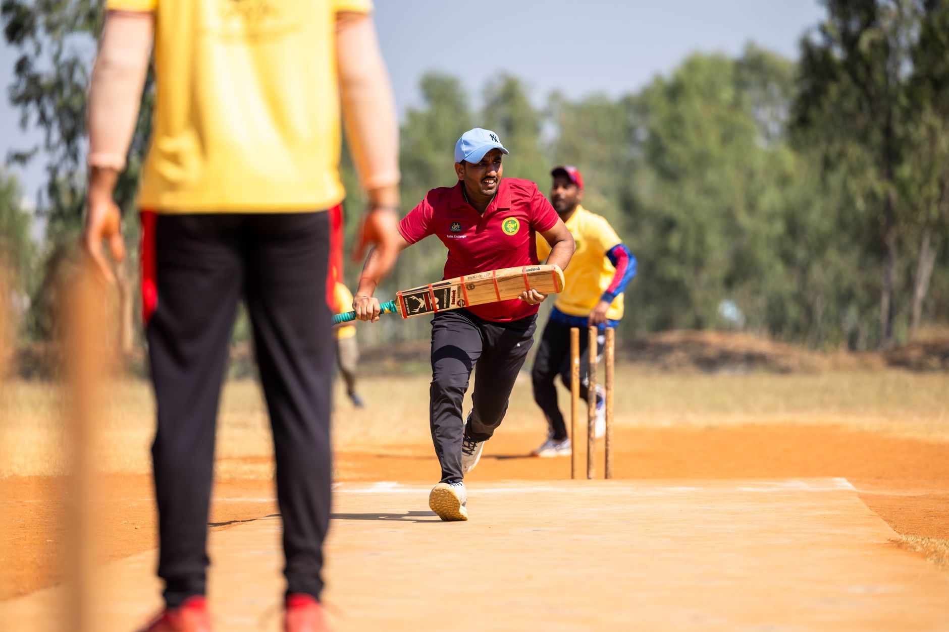 Dynamic scene of a cricket player running between wickets outdoors.