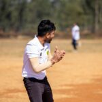 A dynamic shot of a cricketer clapping during an outdoor match on a sunny day.