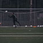 Goalkeeper jumps to save a soccer ball during an outdoor training session on an artificial turf field.
