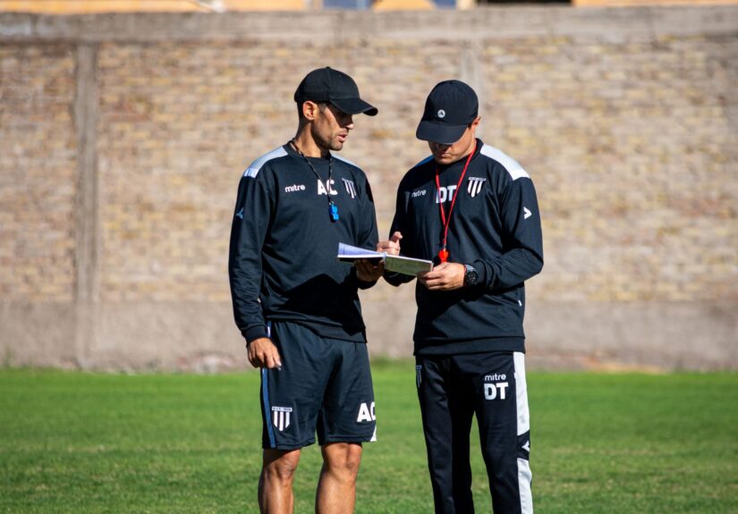 Two soccer coaches reviewing strategies on the field during the day.
