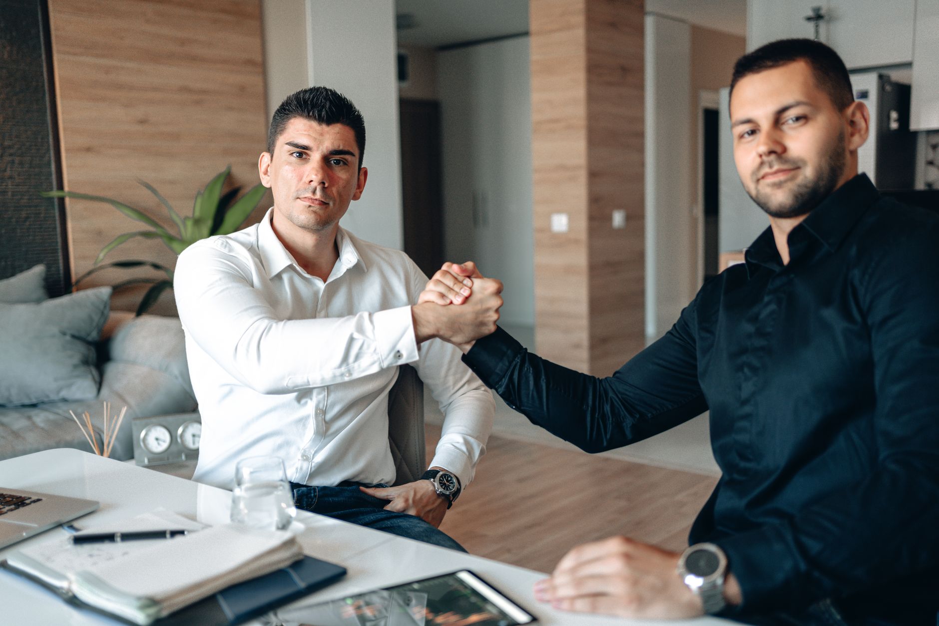 Two businessmen sealing a deal with handshake indoors. Modern office setting.