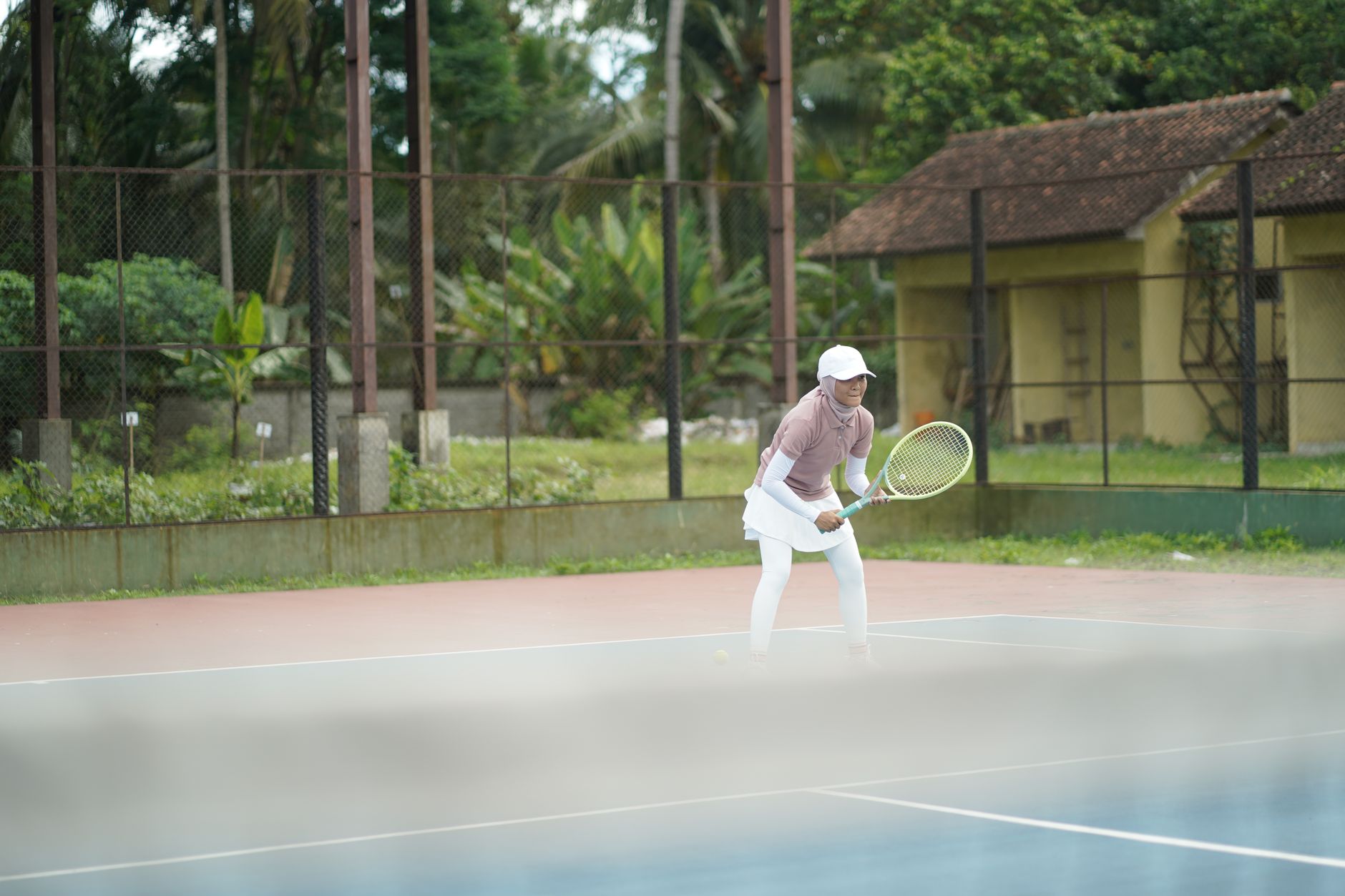 A focused tennis player poised on an outdoor court, capturing the dynamic nature of the sport.