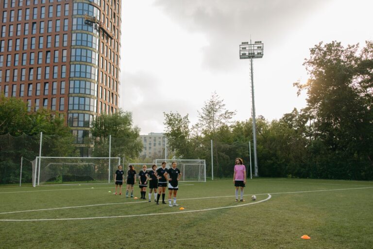 Female athletes training on a soccer field with focus on teamwork and coaching outdoors.