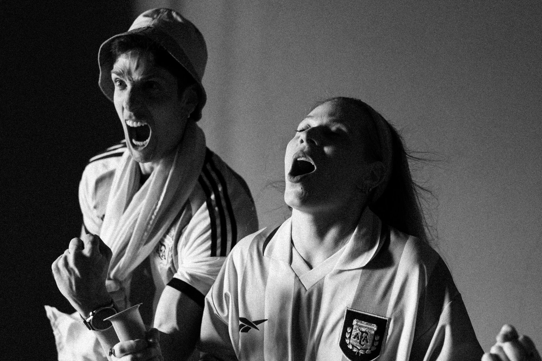 Excited sports fans cheer passionately, capturing the thrill of the game in a black and white photo.