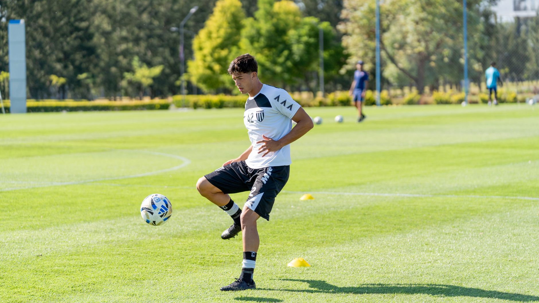A young soccer player practices juggling on a sunny outdoor field, emphasizing athletic dedication.
