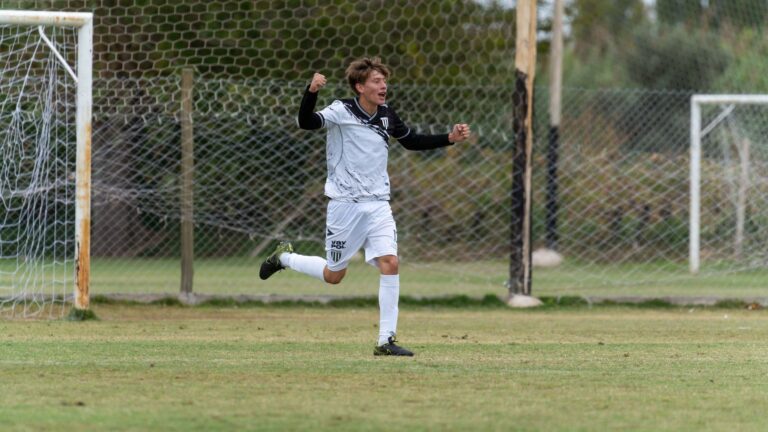 A soccer player in white celebrates a goal on the field, showcasing joy and sportsmanship.