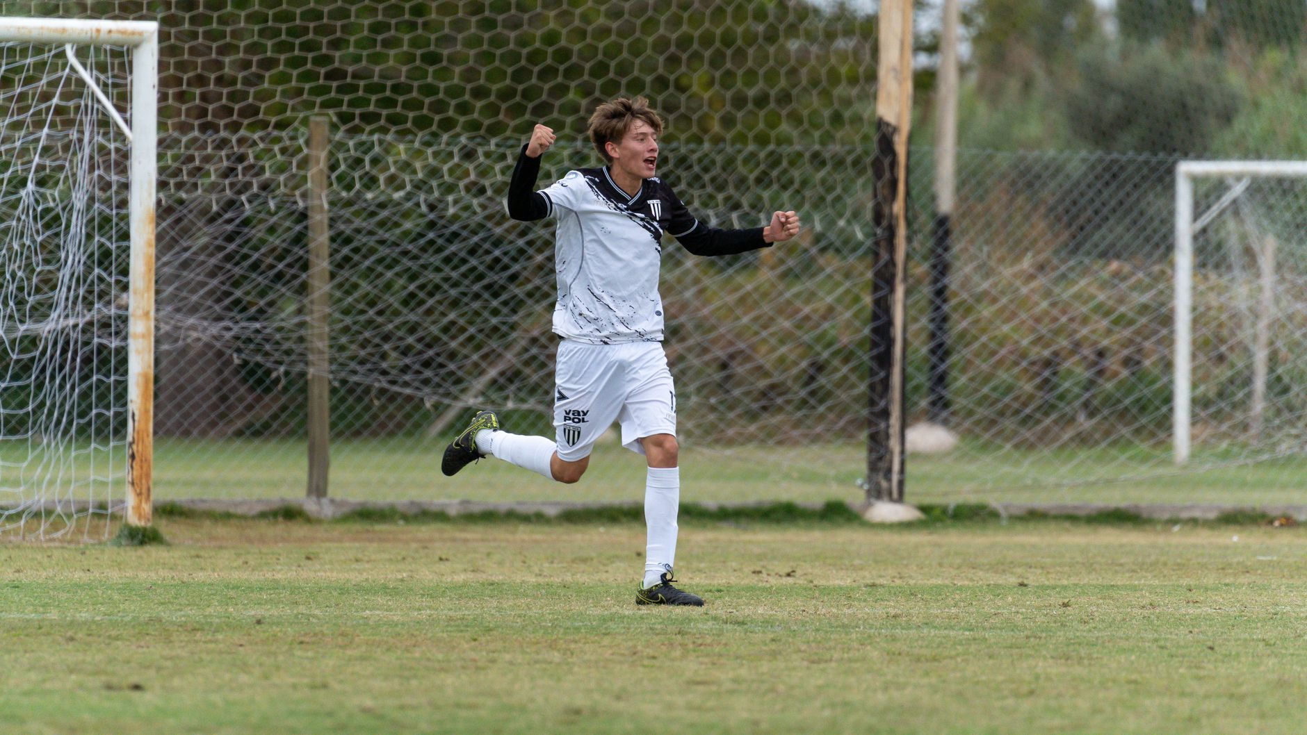 A soccer player in white celebrates a goal on the field, showcasing joy and sportsmanship.