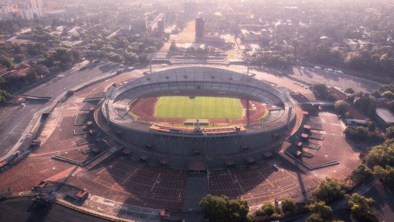 A stunning aerial view of the historic Estadio Olímpico Universitario in Mexico City, surrounded by lush greenery.