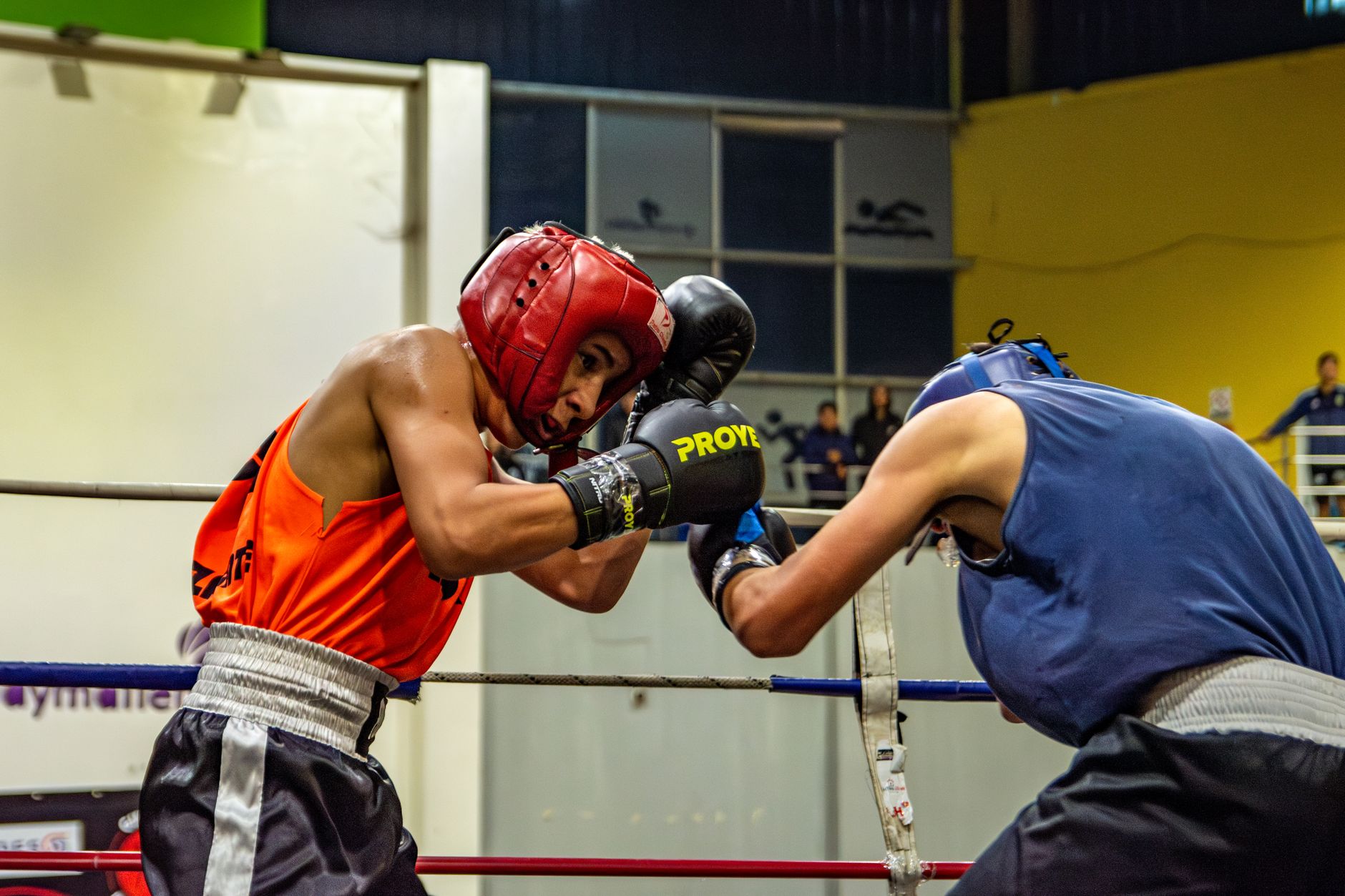 Two athletes engage in a dynamic boxing match, showcasing skill and strength in the ring.