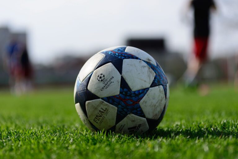 Focus on a soccer ball resting on a vibrant green sports field under daylight.