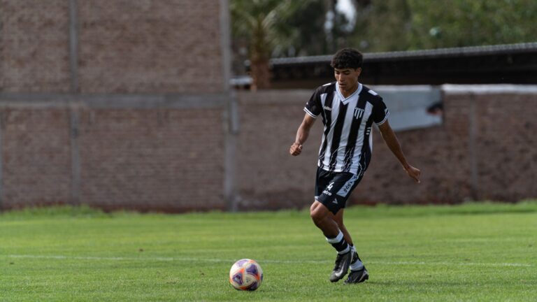 Young male soccer player dribbling on an outdoor field.