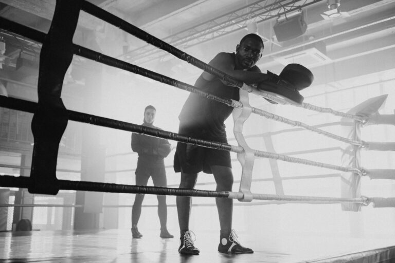 A boxer and trainer in a gym's boxing ring during a training session.