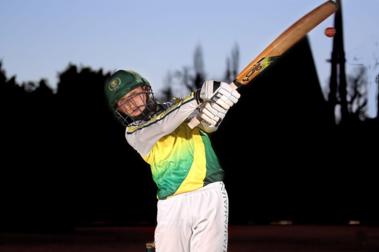 Dynamic shot of a cricketer swinging the bat outdoors in sports gear.