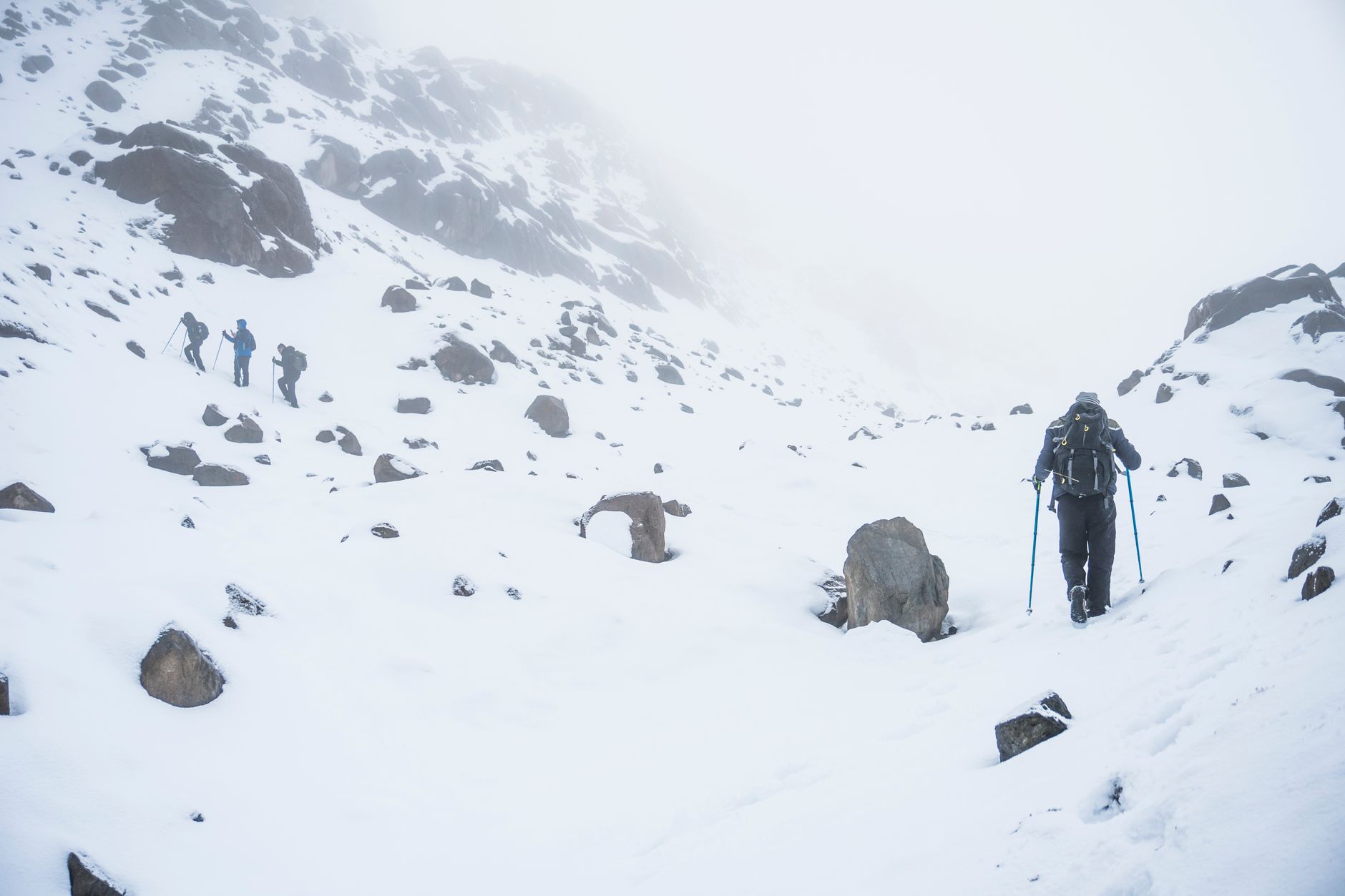Hikers trekking through snowy mountainous terrain in winter, capturing the essence of adventure and exploration.