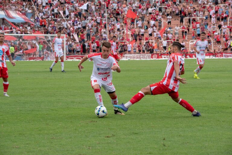 Players in action during a competitive soccer match with a vibrant crowd in the stadium.