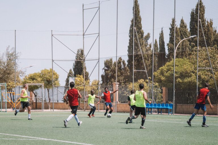 Amateur soccer players enjoy a sunny match on an outdoor field in Málaga, Spain.