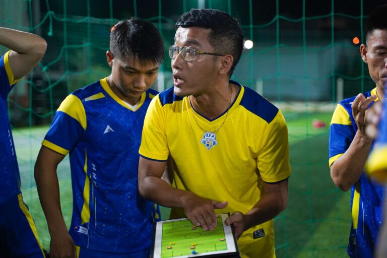 Coach discussing game tactics with soccer team using tablet on the field.