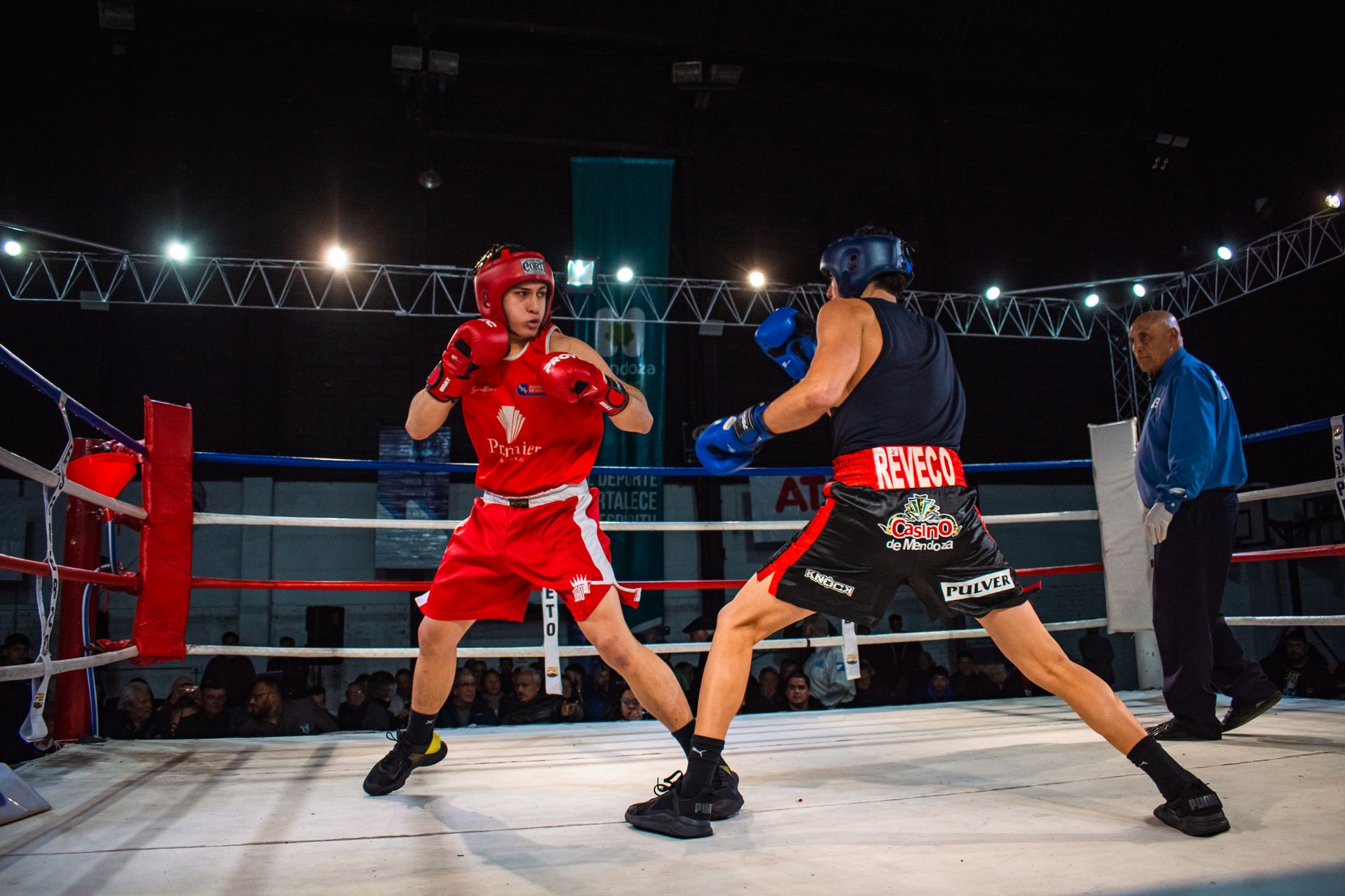 Two amateur boxers in a heated match inside a professional boxing ring.