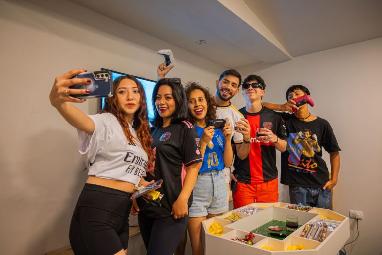 A cheerful group of friends having fun indoors, playing video games and taking selfies.