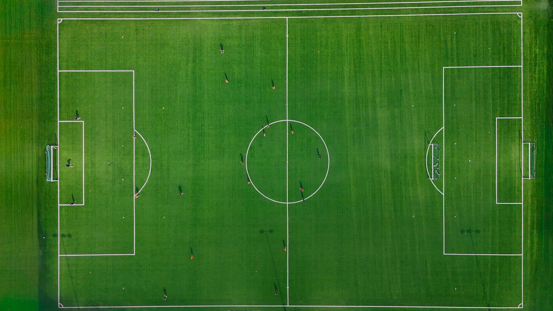 Aerial shot of a soccer field with players in Jönköping, Sweden, showcasing vibrant green grass.