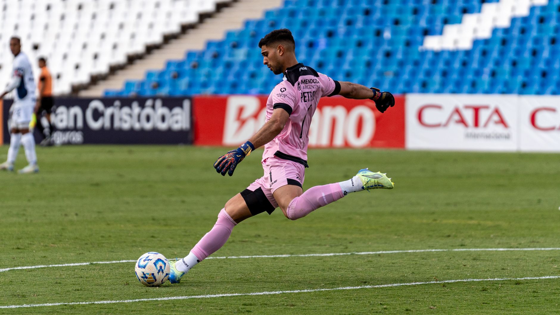 Dynamic shot of a goalkeeper in pink uniform kicking a soccer ball.