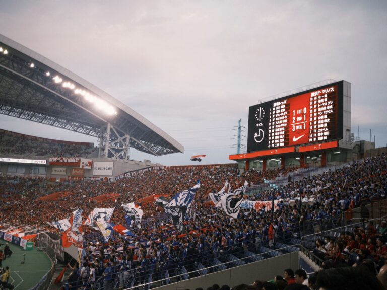 A lively soccer stadium scene with fans waving flags and a scoreboard displaying match details.