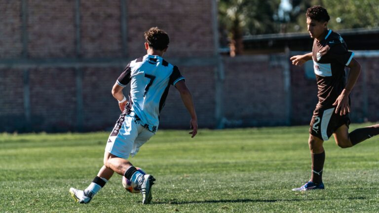 Two soccer players in action during an outdoor daytime match on a grassy field.