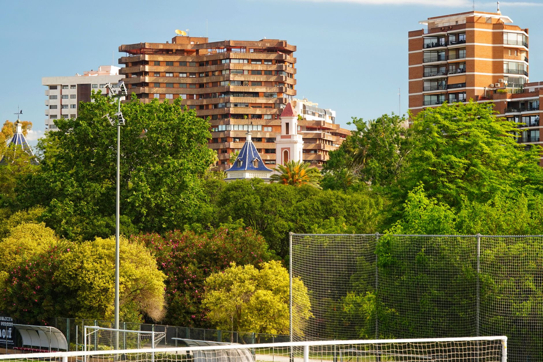 Scenic urban park with lush trees and residential buildings, captured in daylight.