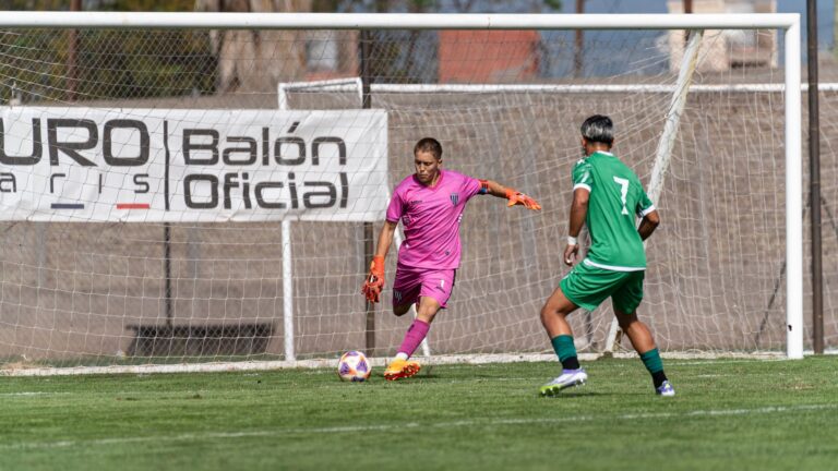 Goalkeeper in pink uniform and player in green during intense soccer match outdoors.