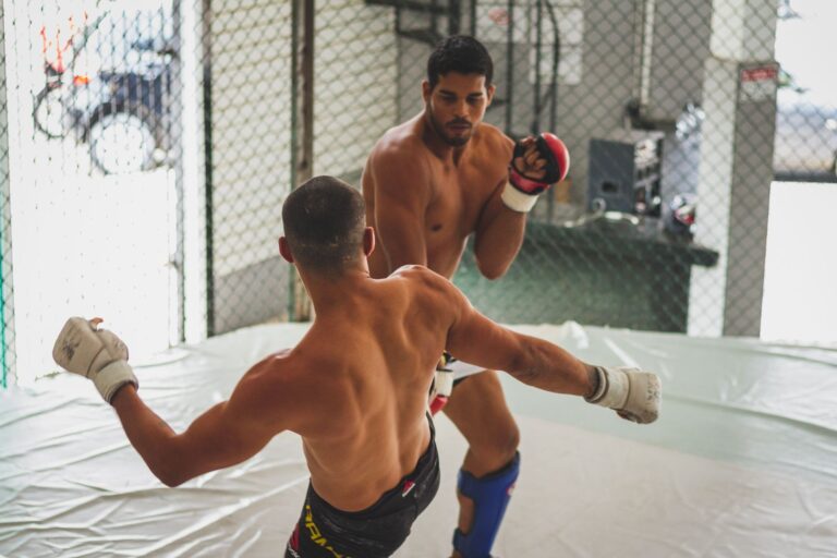 Two male fighters sparring in an indoor gym for martial arts practice.