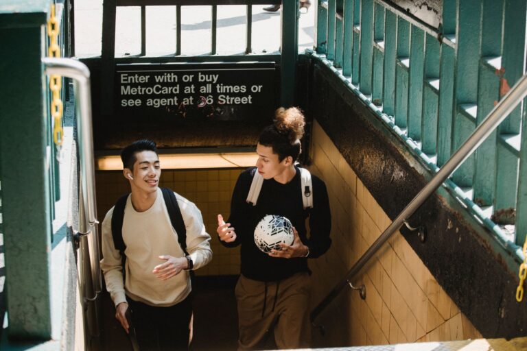 From above of friends with backpacks and ball talking to each other while exiting subway station