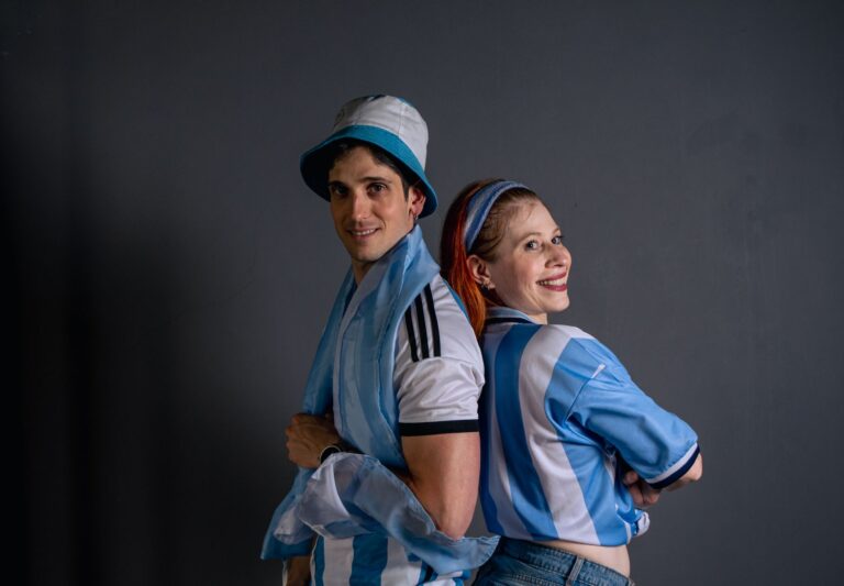 Happy soccer fans in blue and white jerseys celebrating sports indoors.