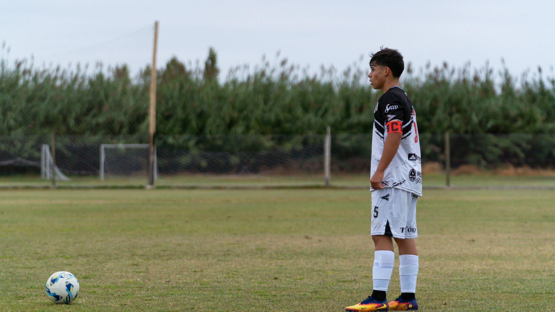 A young soccer player stands ready on the field, wearing team uniform. Perfect for sports-themed imagery.