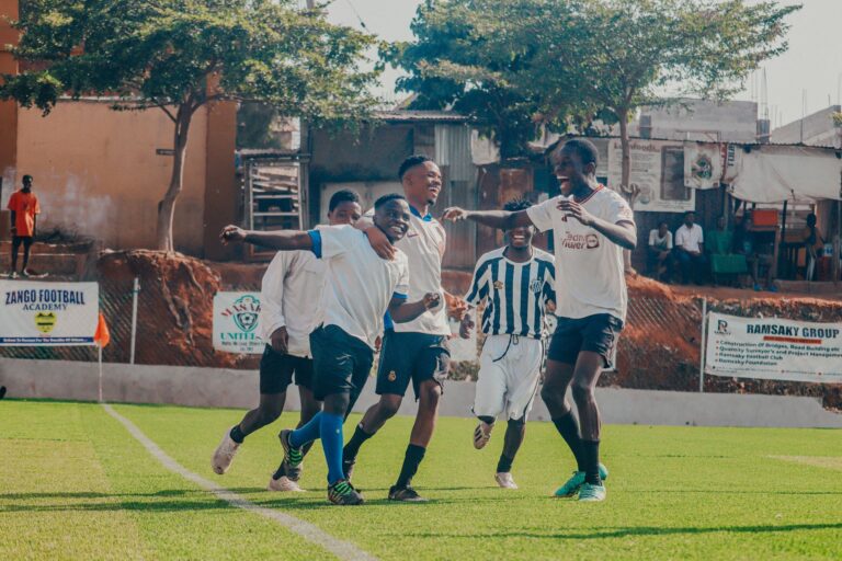 Excited young soccer players celebrating a goal on a sunny day on the football field.