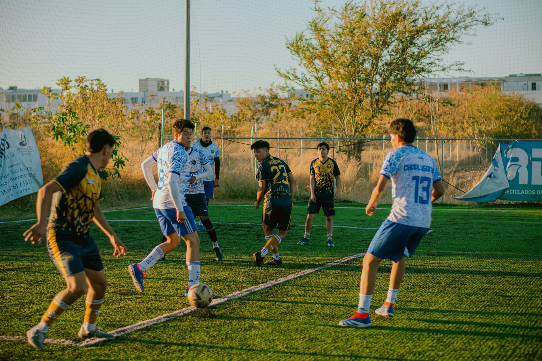 Teen soccer players compete on a field at sunset, showcasing vibrant energy and teamwork.