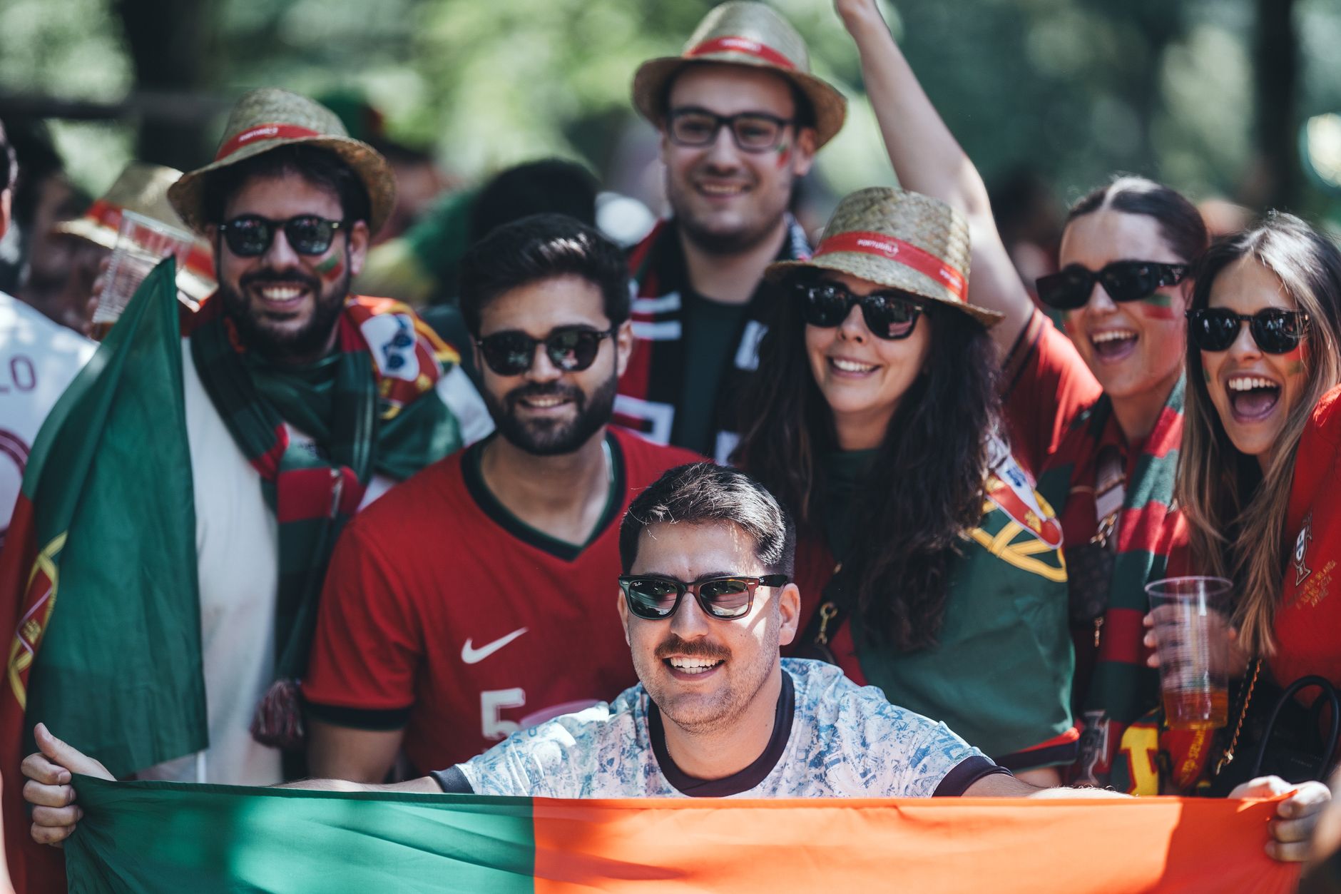 A joyful group of friends celebrating with flags, showing unity and excitement outdoors.